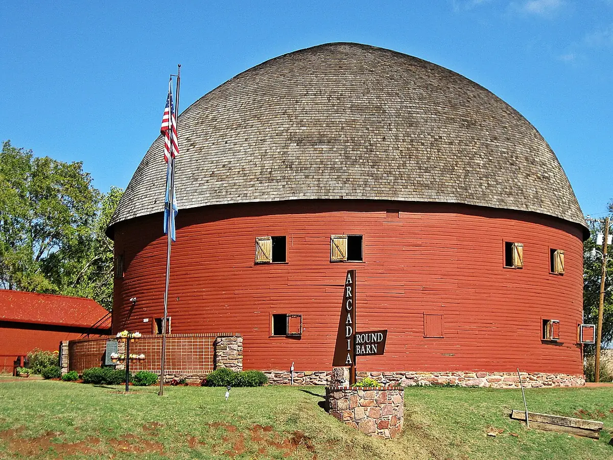 The red, dome-roofed Arcadia Round Barn on Route 66 under a blue sky