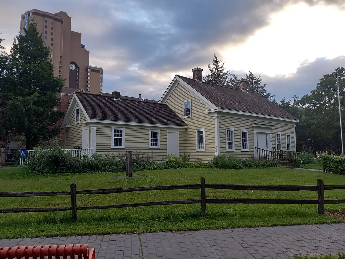 The pale yellow clapboard Ard Godfrey House behind a rail fence in Minneapolis