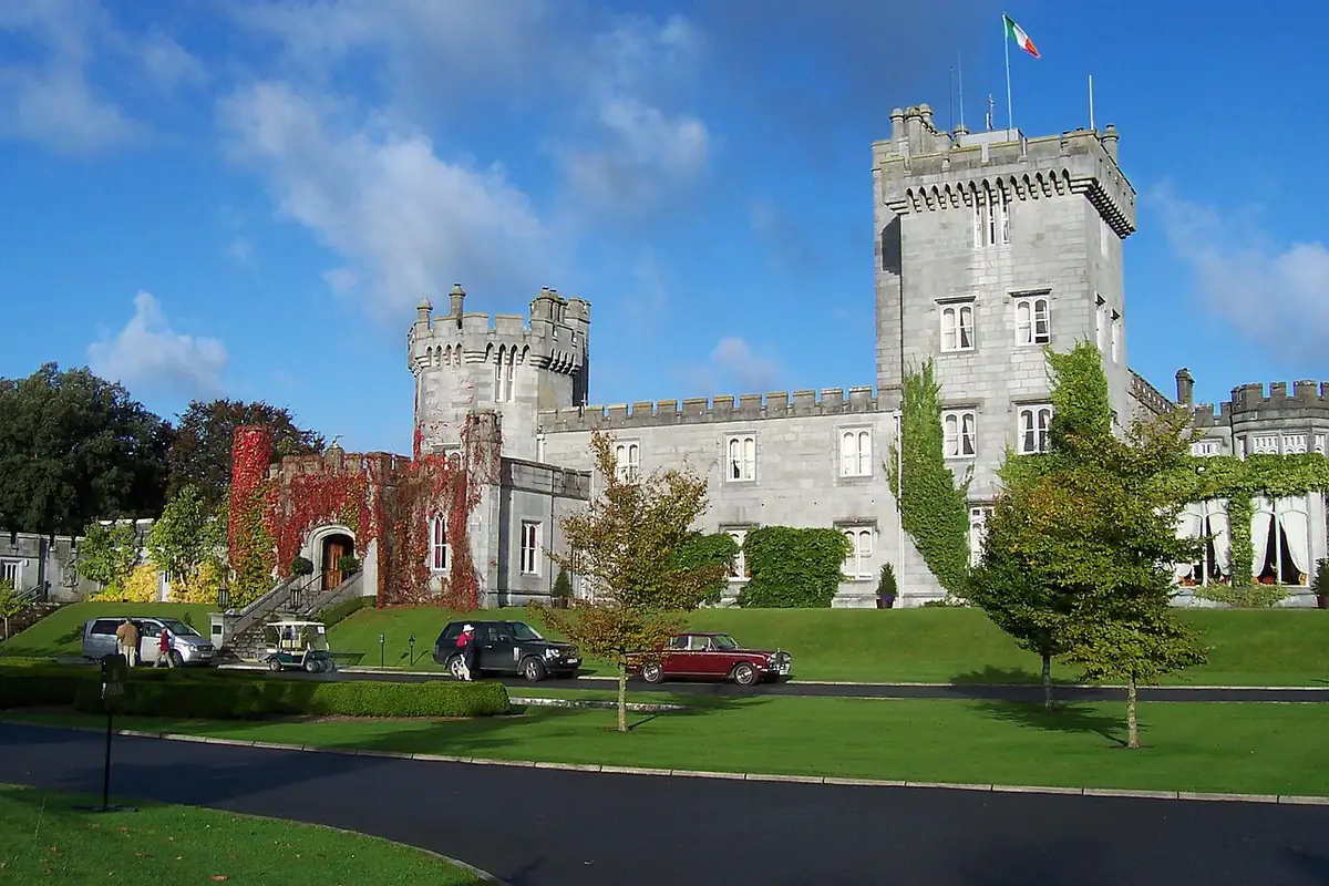Gray stone towers of Dromoland Castle with a flag flying above the drive