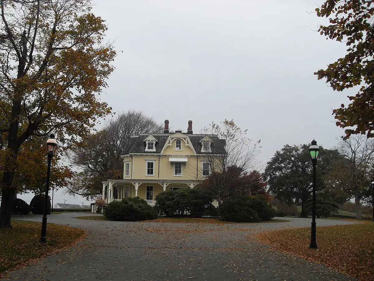 Yellow mansard-roofed Eisenhower House among autumn trees at Fort Adams, Newport