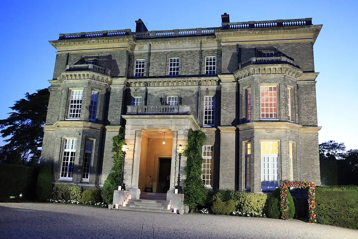 Hedsor House's stone front and entrance lit at dusk