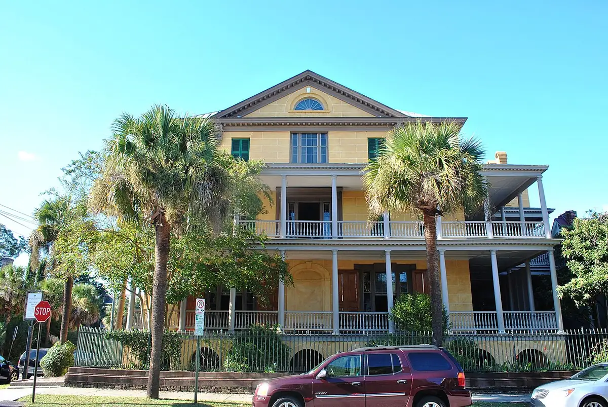 Three-story yellow William Aiken House with double piazzas and palms in Charleston